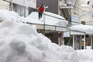 雁木の雪下ろしをする住民＝４日、長岡市殿町３

