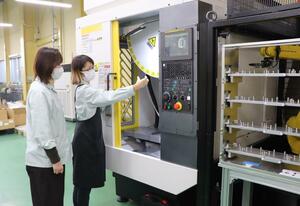 新たに導入された工作機械を点検するアサヒプレシジョンの社員＝長岡市