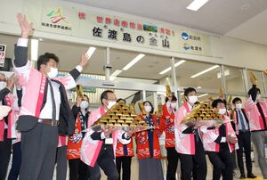 「佐渡島の金山」の推薦決定を祝う横断幕の下で喜ぶ佐渡市の観光関係者。曲折を経て、ようやくハードルの一つを越えた=29日、佐渡市の佐渡汽船両津港ターミナル