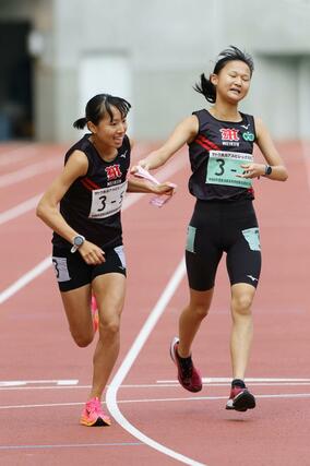 女子 新潟明訓の4区高山光帆(右)がアンカー石川桃子にタスキをつなぐ=新潟市中央区