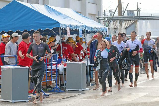 スイム直後の水分補給スポット。選手たちはすぐにバイクへと向かう＝９月１日、佐渡市
