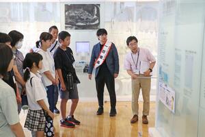 1日館長のたすきを掛けた高橋なんぐさんとともに新潟水俣病を学ぶ子どもたち=2日、新潟市北区