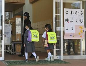 「これから仲よくしよう」のボードが掲げられた石川県能登町立柳田小に入る輪島市立町野小の児童ら=昨年10月、能登町