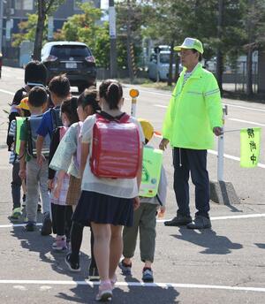 地域のボランティアに見守られながら登校する児童たち=6月6日、上越市