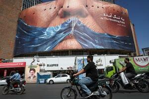 テヘラン市内に掲示された「ホルムズ海峡で口をふさがれたトランプ大統領」のイラスト=25日(ロイター=共同)
