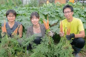 収穫したニンジンを手にする岩本菜々さん(中央)ら=7日、東京都八王子市