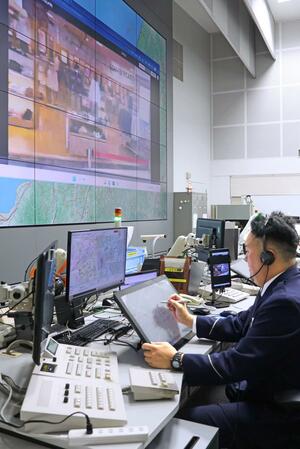 通報を受ける警察官と、システムを活用して映し出された映像＝１０日、県警本部