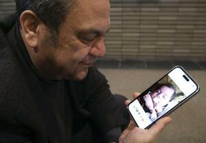 テヘランに住む兄の孫の写真を見つめるハミッド・エスハーギさん＝３月５日、大阪市住吉区