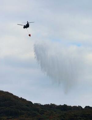 　大分市佐賀関の大規模火災現場付近で上空から散水する自衛隊のヘリコプター＝２０日午前１０時２６分