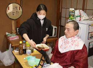 お年寄りの自宅で介助するベトナム出身のドーティフォン・ラムさん＝佐渡市赤泊