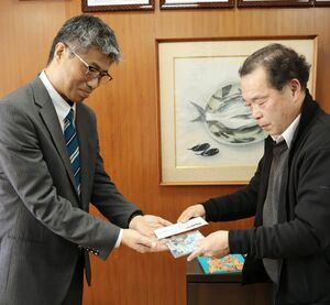 自作の民話を収録したCDと売り上げの寄付をした新田晃山さん(右)と赤泊小の土屋雅朗校長=佐渡市赤泊