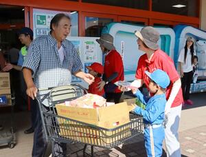 白バイ隊員に扮した園児が交通安全を呼びかけナスの漬物を配布した=聖籠町蓮野