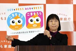 　「こまもろう」のパネルを見せる渡辺由美子こども家庭庁長官＝２０２５年１２月、東京・霞が関