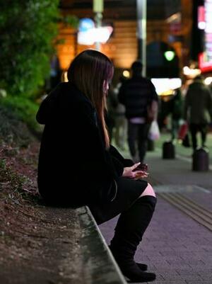 　かつて通った東京・歌舞伎町で植え込みに腰かける女性＝２月