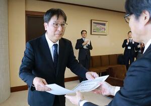 「へき地医療功労歯科医師」の表彰状を受け取る片海正明さん（左）＝１２日、県庁