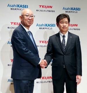 記者会見で握手する帝人フロンティアの平田恭成社長(左)と旭化成アドバンスの春見恵司社長=2日午後、東京都内