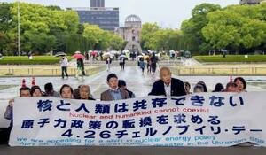 　チョルノービリ原発事故から４０年を迎え、脱原発を訴えて座り込みを行う人たち＝２６日午後、広島市の平和記念公園