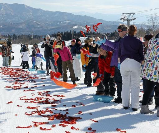 好天の中、トウガラシを雪に投げる外国人観光客ら=20日、妙高市