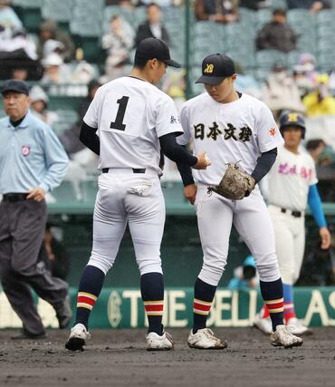 １０点を追う日本文理４回２死二塁、先発した染谷崇史（左）からマウンドを引き継いだ箕浦環太＝２５日、甲子園球場