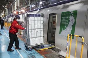 荷物専用新幹線から積み荷を降ろす作業員＝２３日、東京都北区の車両基地