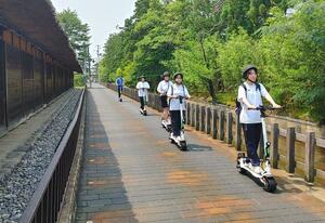 電動キックボードで観光スポットを巡る商業クラブのメンバー=新発田市諏訪町3