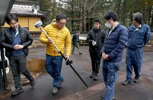 最新の測量機械を試す平成測量の社員と鈴木祐太社長(左)=上越市頸城区