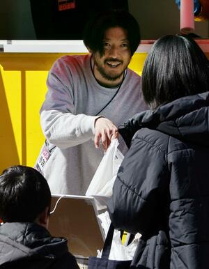 自身のチョコブランドが出店したスタジアムで、商品を手渡す清水慶記さん=2月、前橋市