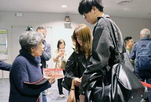 韓国便の乗客にチラシを手渡し、情報提供を情報を求めた中村クニさん=7日、新潟空港