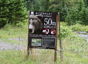 　岩尾別地区にあるヒグマと適切な距離を保つことを呼びかける看板＝２０日、北海道斜里町