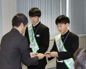 関係者と名刺交換をする、一日税務署長の榊原愛琉さん(中央)と上之山篤人さん(右)=佐渡市相川三町目新浜町