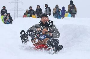 雪のアトラクションを楽しむ家族連れら=1日、長岡市栃尾宮沢