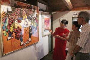 故郷・佐渡の伝統芸能や風景を題材にした作品ついて来館者らに説明する吉田志麻さん(左)=7月6日、新潟市西蒲区越前浜