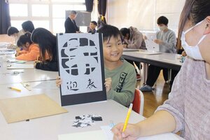 上手に切り抜いて完成させた袴紙を親に見せる児童=佐渡市入川