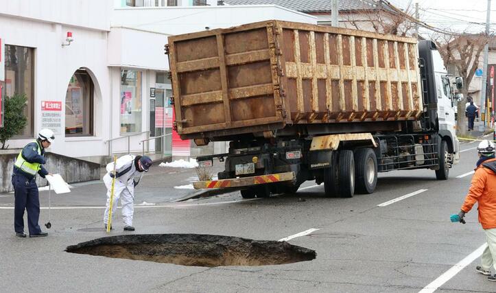 陥没した道路と、はまった車両＝９日、新潟市東区太平４