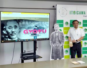 相馬御風を題材にした映画の予告編の画面と、御風の著書を持つ久保田郁夫市長=糸魚川市役所