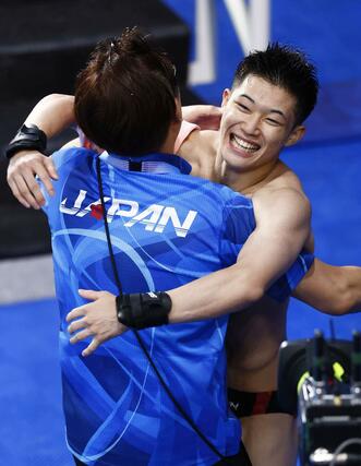 パリ五輪の男子高飛び込み決勝で演技を終え、馬淵崇英コーチ（左）と抱き合う玉井陸斗。銀メダルを獲得した＝８月１０日、パリ郊外（共同）
