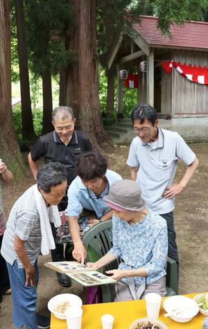 「八幡社」の神事に参加した峠集落の出身者。アルバムを見ながら思い出話に花を咲かせた=長岡市川口峠