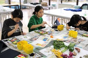 真剣な表情で絵手紙の年賀状を描く津川小児童=阿賀町津川