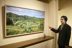 十日町市の棚田を描いた作品について説明する橋本直行さん=弥彦村弥彦