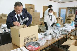 被災地に届ける台所用品を梱包する関係者ら=30日、燕市物流センター