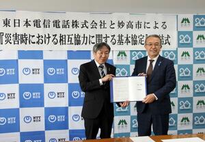 災害時の相互協力に関する基本協定書を手にする城戸陽二・妙高市長(右)と石井宏明・NTT東日本新潟支店長=妙高市役所