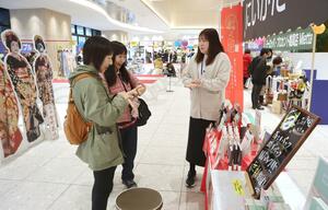 出店ブースで商品の説明を受ける買い物客=22日、新潟市中央区