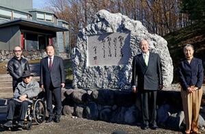 「富良野演劇工場」に寄贈した石碑の前で記念撮影する倉本聰さん(左端手前)=16日午前、北海道富良野市