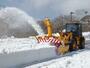 青空に向かって雪を勢いよく飛ばす除雪車＝３日、佐渡市の大佐渡スカイライン