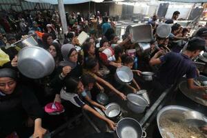 ガザ中部ヌセイラト難民キャンプで、配給の食べ物を受け取ろうとする人たち=16日(ゲッティ=共同)