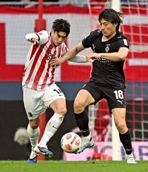 競り合うフライブルクの鈴木唯(左)とボルシアMGの町野=フライブルク(共同)