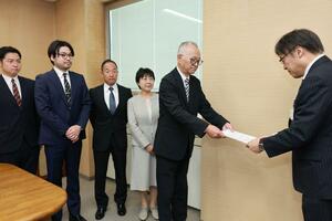 太田勇二県教育長(右)に要望書を手渡す村上高同窓会長の圓山文堯さんら関係者=県庁