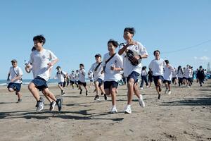 がんばり行軍がスタートし、一斉に走りだす直江津中の生徒たち=上越市の郷津海岸