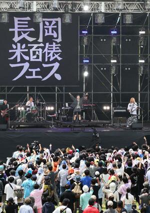 ステージで熱唱するアーティストと盛り上がる観客たち=23日、長岡市の国営越後丘陵公園