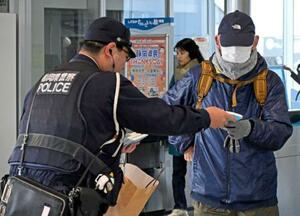 JR天竜川駅で利用者に事件の概要が書かれたチラシ入りティッシュを手渡す警察官=27日午前、浜松市
